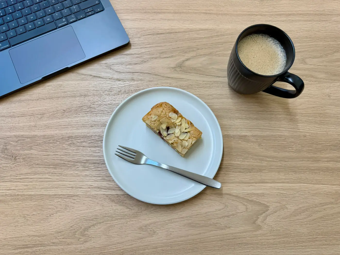 A laptop, coffee, and a slice of cake on a desk at Pershore Coworking