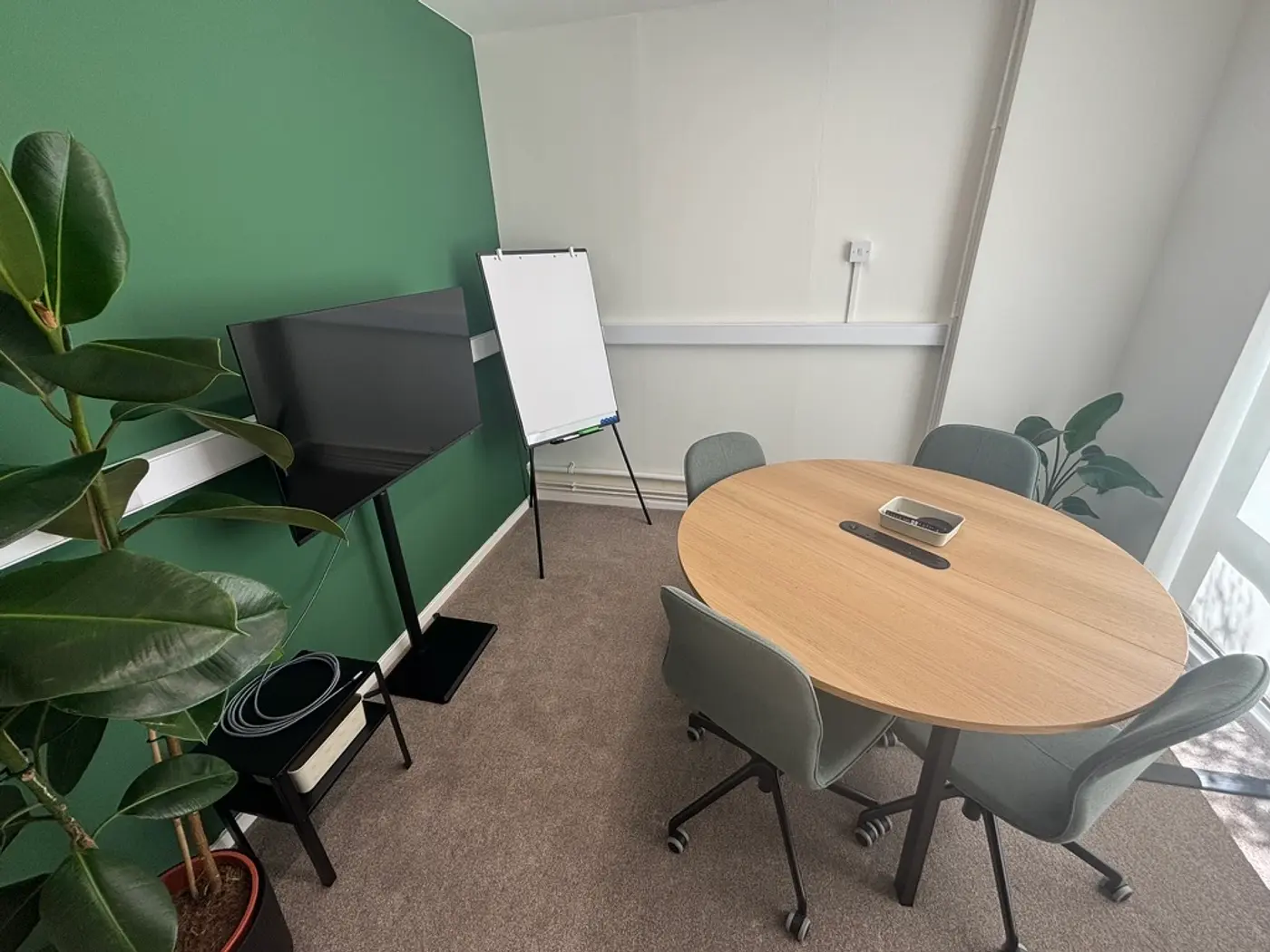 The meeting room at Pershore Coworking, with a round table, screen, and flipchart