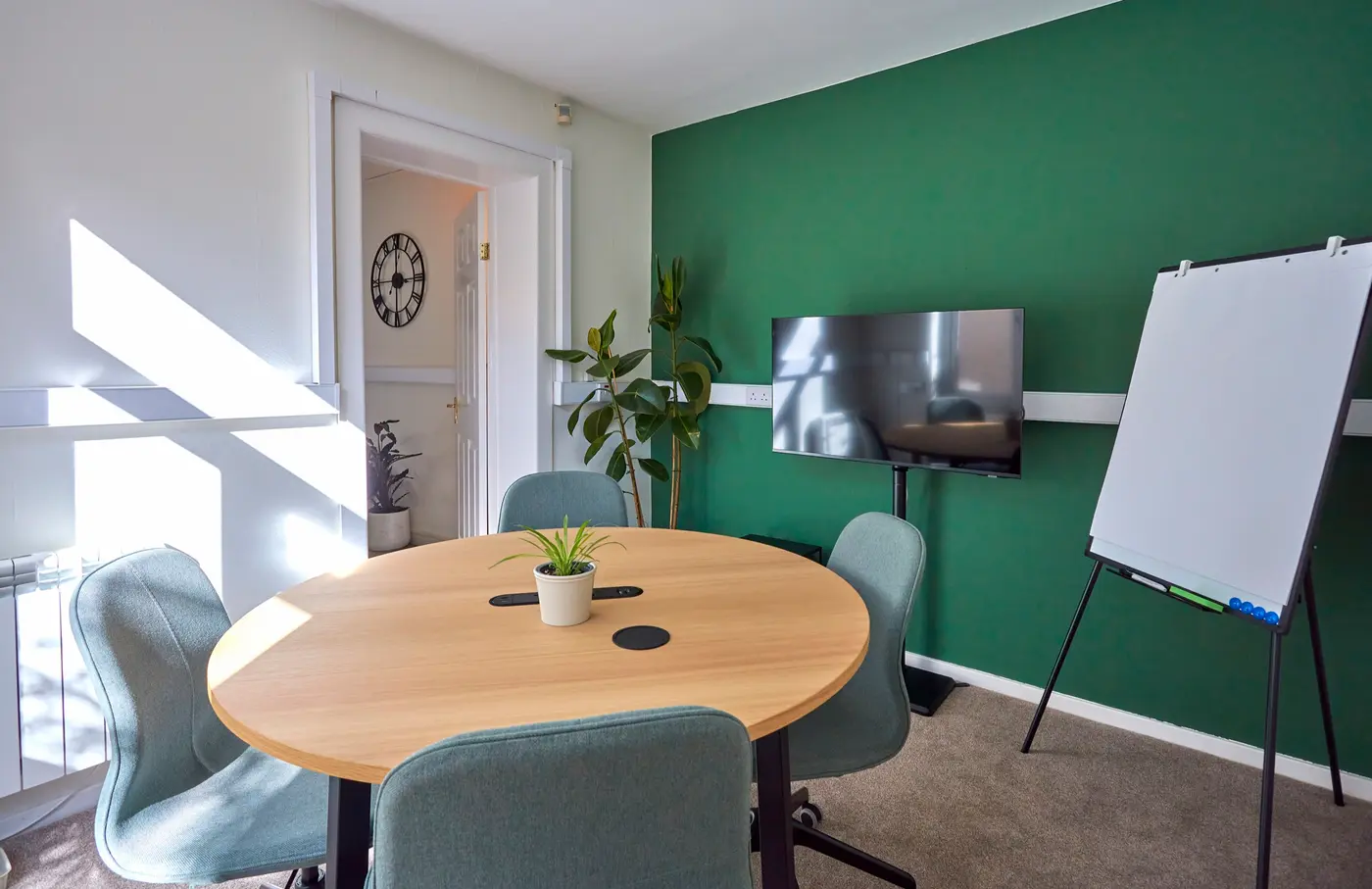 The meeting room at Pershore Coworking, with a round table, screen, and flipchart