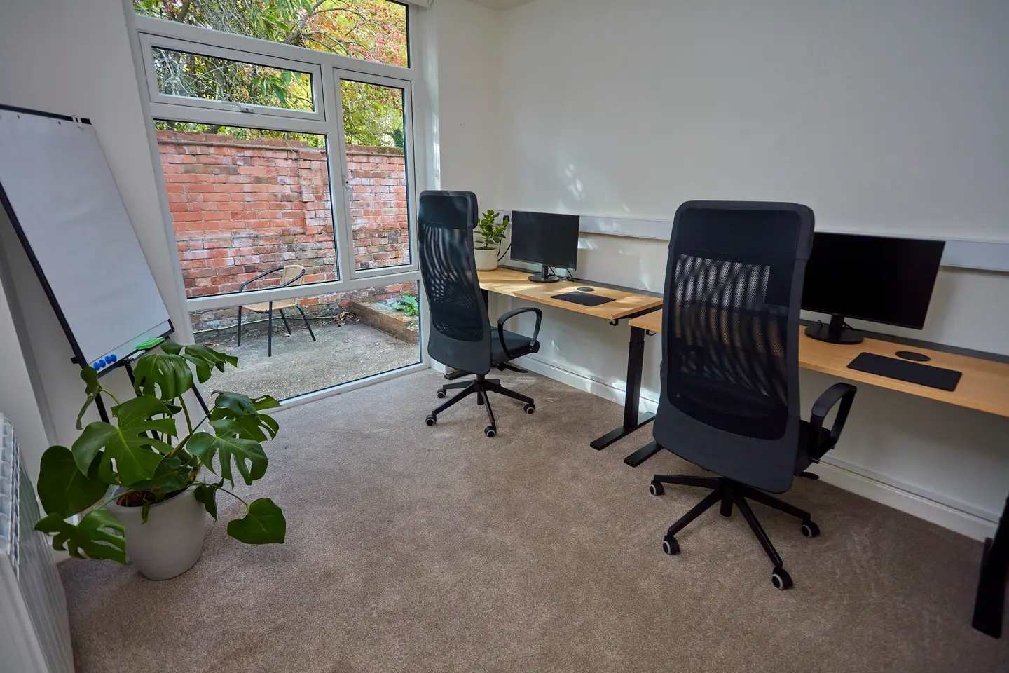 A private workspace at Pershore Coworking with two desks, a flipchart, and a door onto the garden